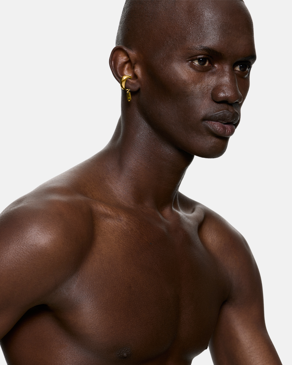 Model wearing the Blown Charm Green Ear Cuff in Gold Vermeil with a suspended green baguette cubic zirconia. Styled as a sculptural statement ear cuff.