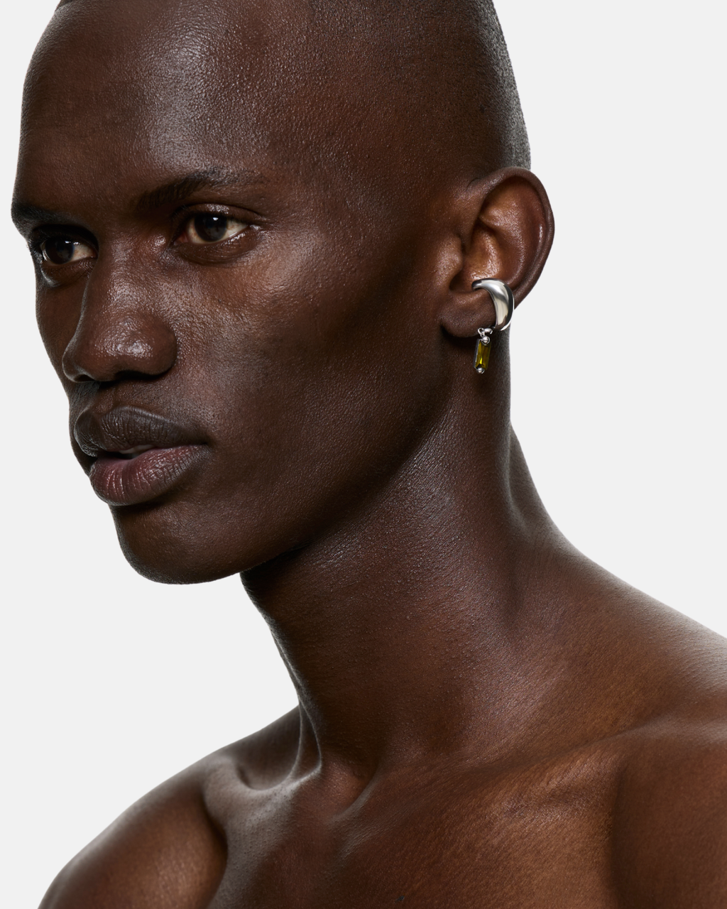 Model wearing the Blown Charm Green Ear Cuff in Rhodium Vermeil with a suspended green baguette cubic zirconia. No piercing required.