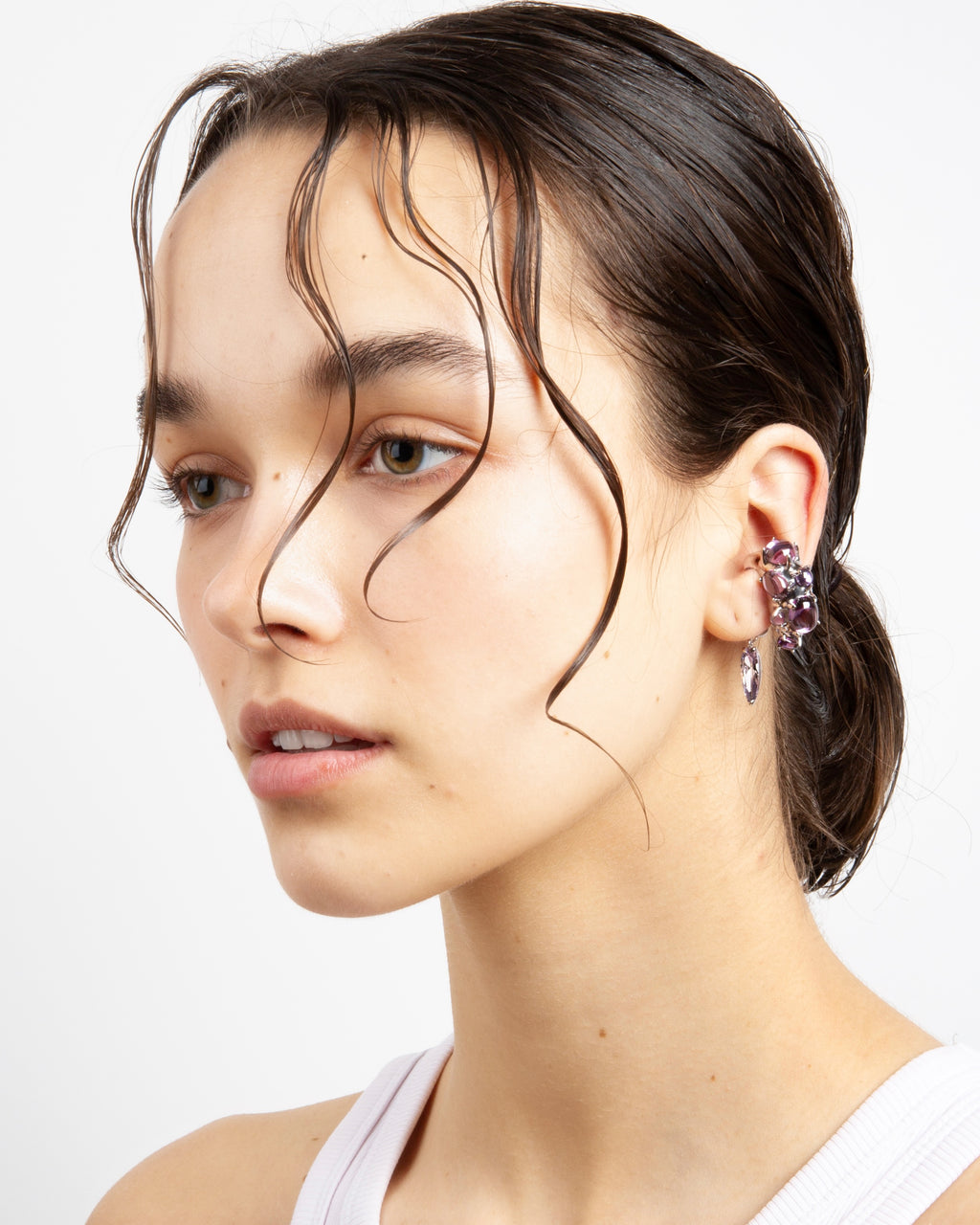 Model wears Alan Crocetti rhodium vermeil ear cuff with purple cabochons and drop charm